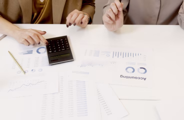 Two professionals analyzing financial documents with a calculator.