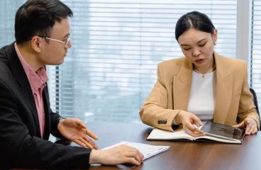 Two business professionals discussing documents in a modern office.
